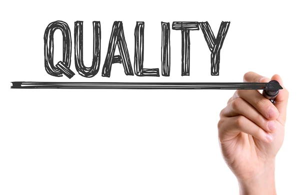 Hand drawing the word 'QUALITY' with a black marker, emphasizing the concept of high standards and excellence.