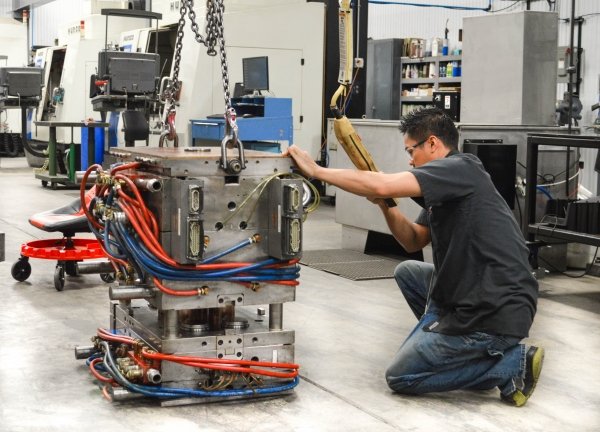 "Factory worker maintaining a plastic slipper mold to prevent burrs and flashes in production."